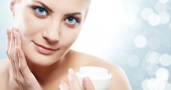 Woman applying moisturizer cream on face.