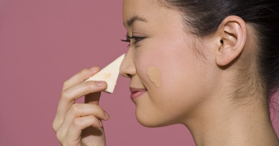 Woman applying makeup foundation