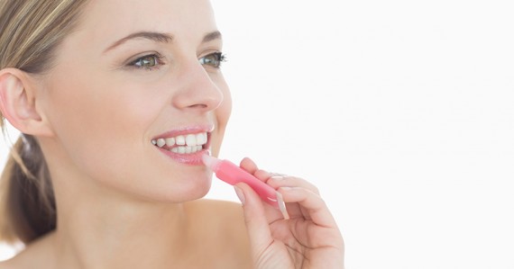 Close-up of young woman applying lipgloss